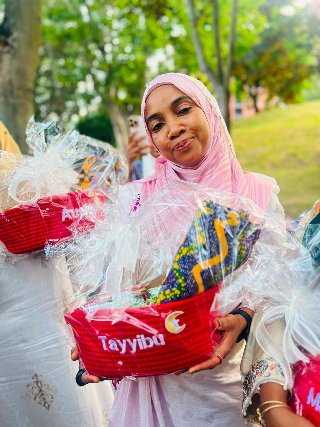 A smiling member holding a gift hamper