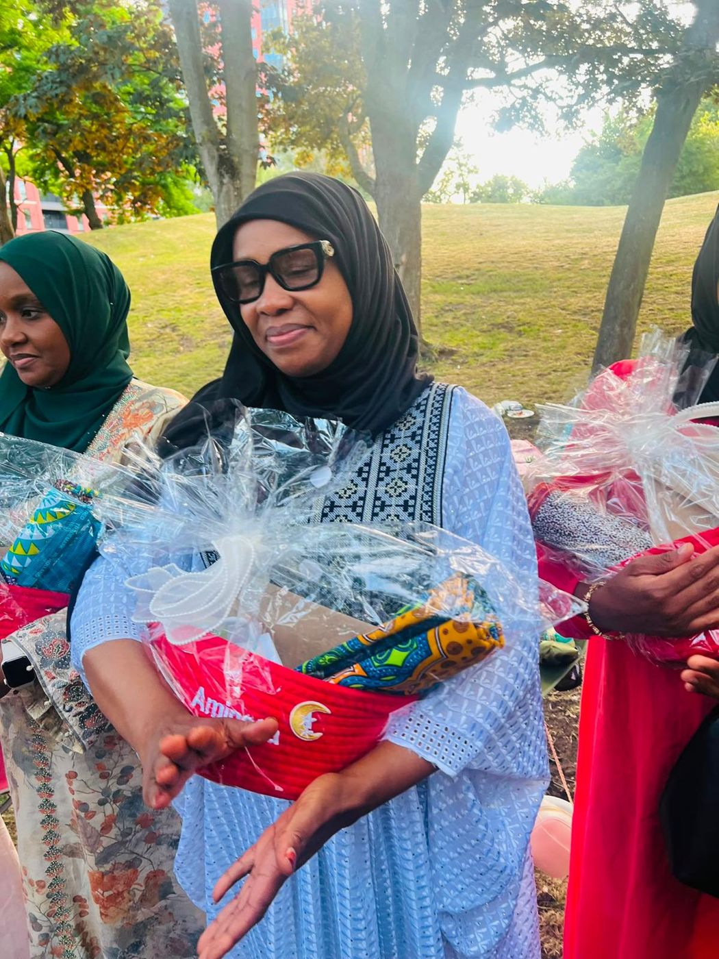 A member holding a gift hamper beside other members