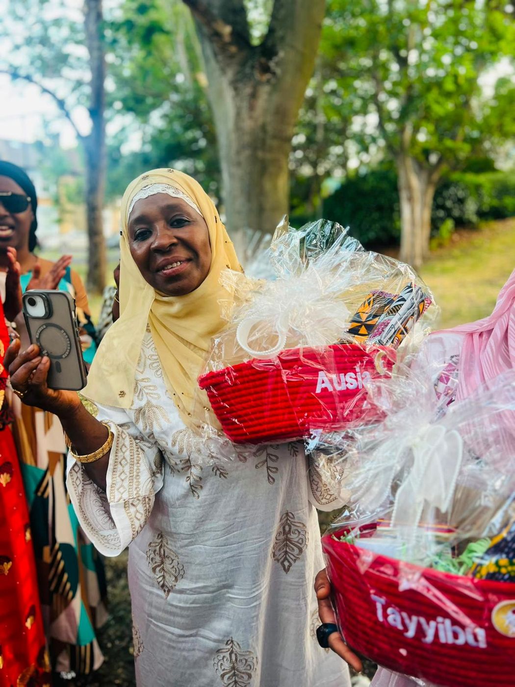 A smiling member holding a named gift hamper