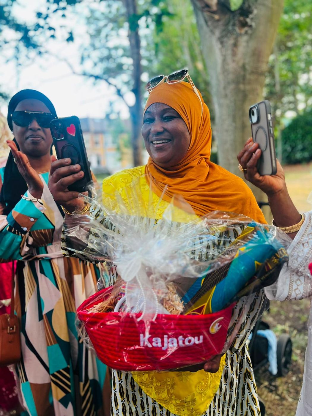 A member in an orange headscarf holding a named gift hamper