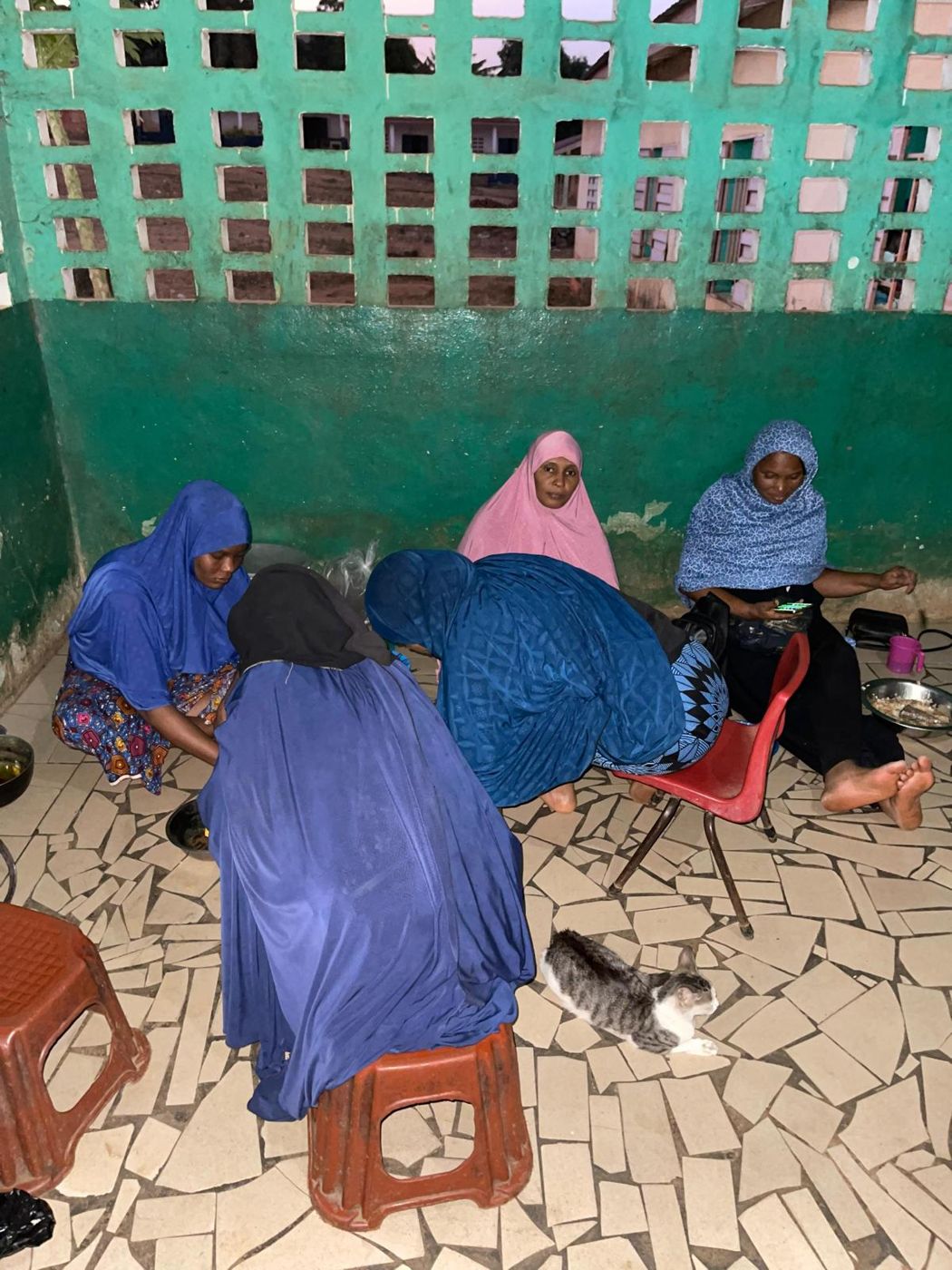 Women in headscarves sitting together preparing food
