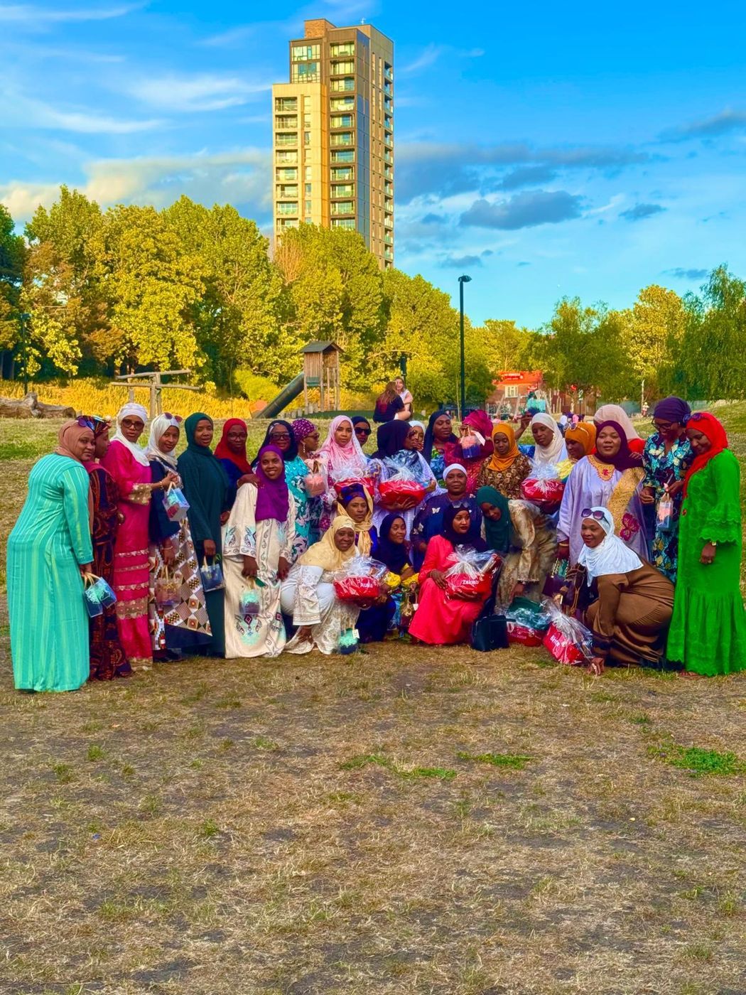 A large group of association members gathered in a park on a sunny day