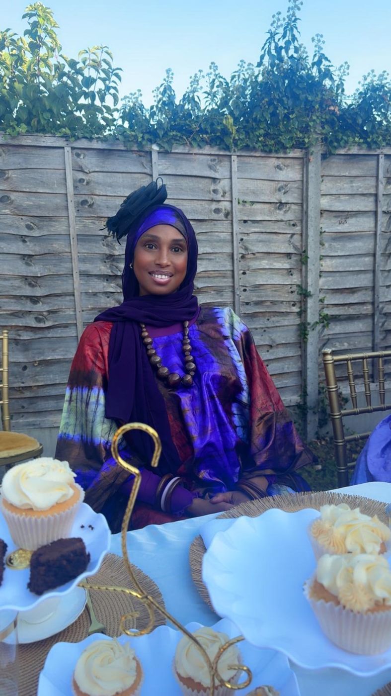 A member seated beside a table of cupcakes and pastries