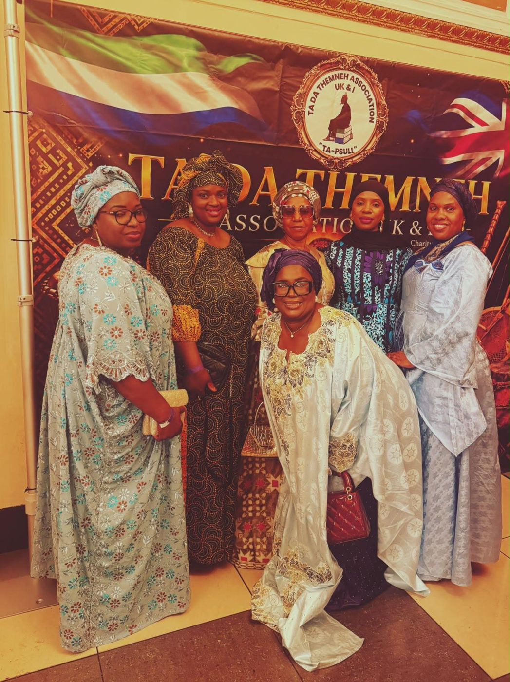 Members in traditional dress in front of an association banner