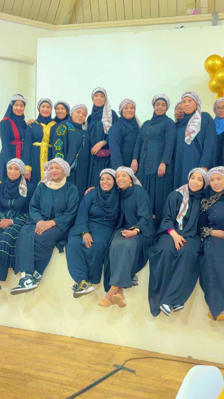 A large group of members in navy dresses posing on a stage