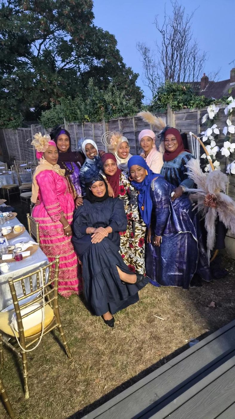 Members gathered by the floral arch at an evening garden event