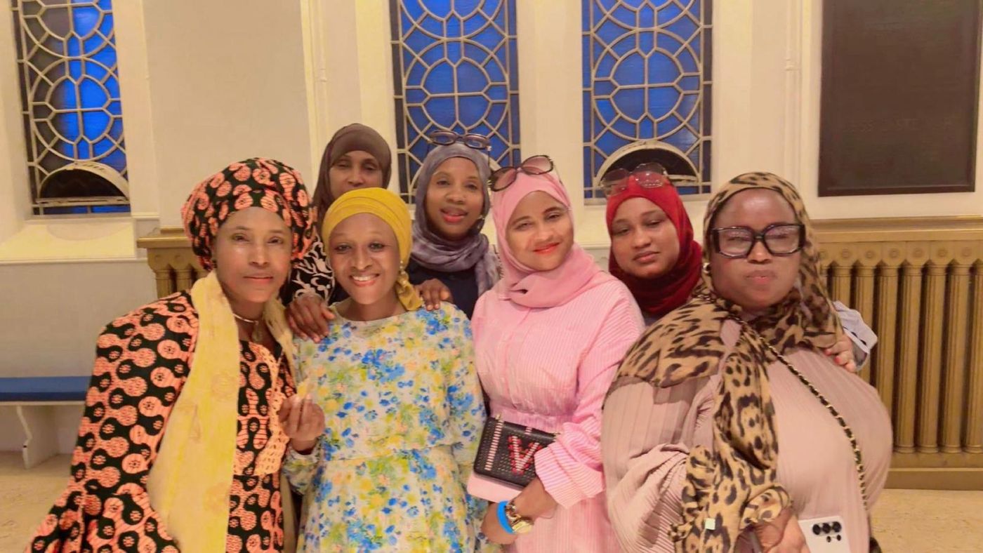 Members in patterned headwraps smiling together indoors