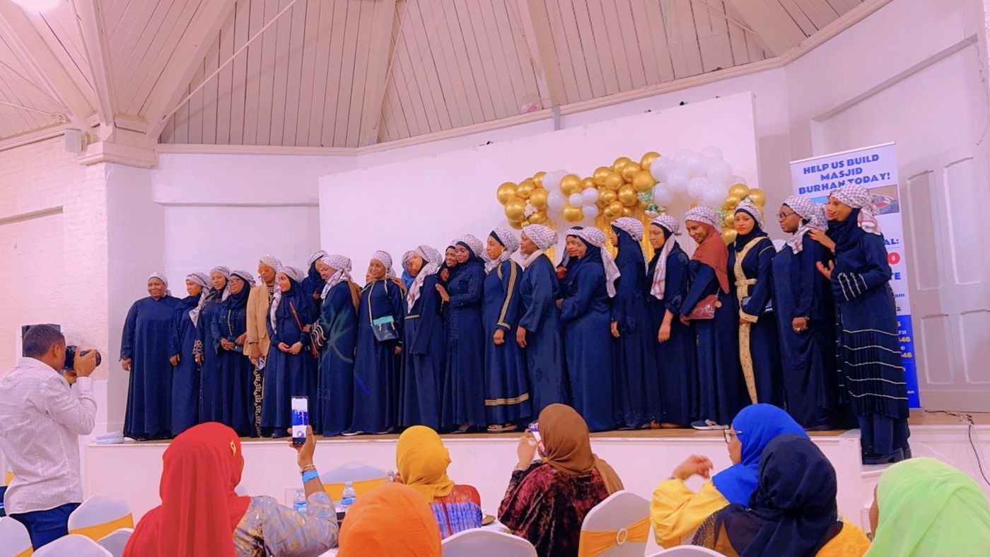 Members in matching navy gowns on stage at a celebration