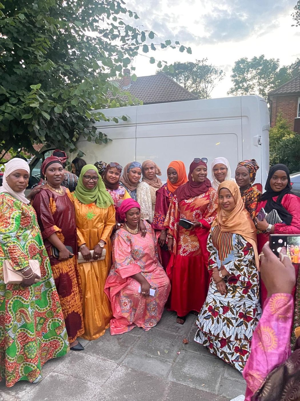 A large group of members in colourful gowns gathered outdoors