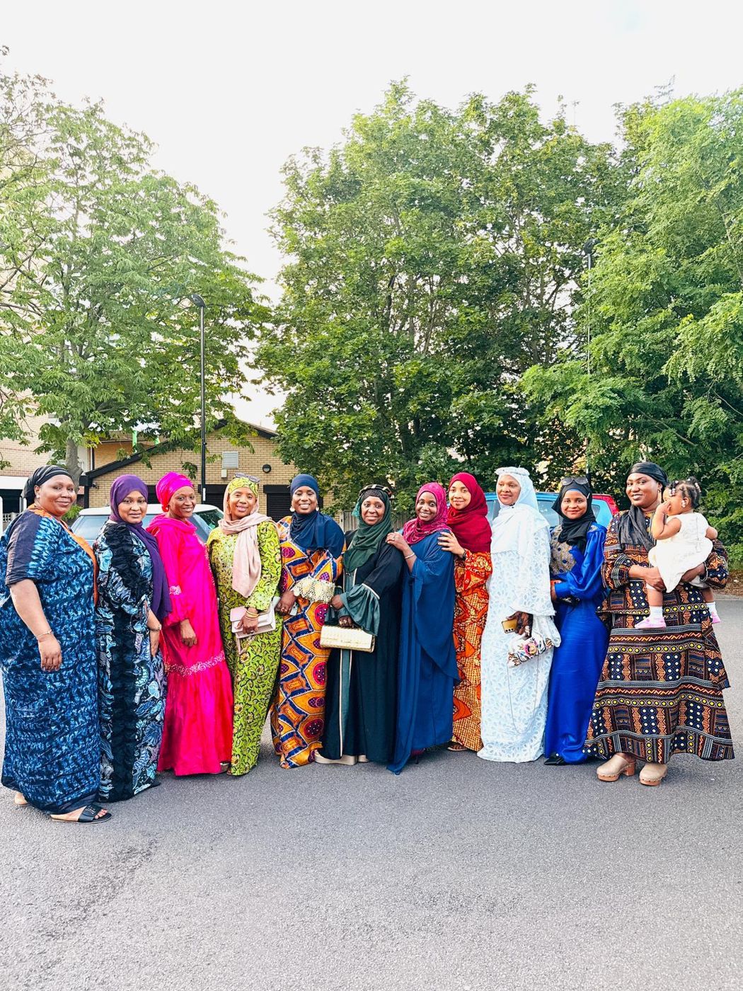 Members in brightly coloured traditional gowns standing outdoors