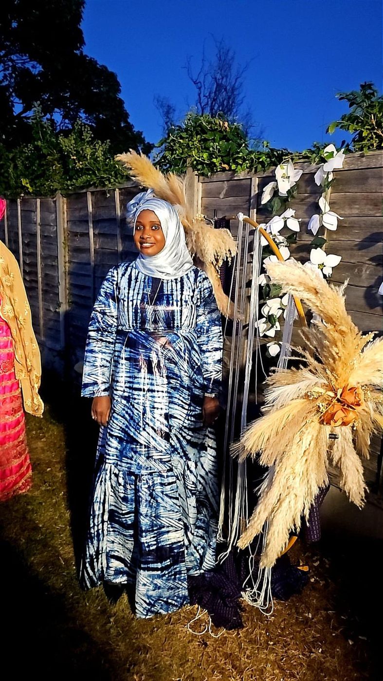 A member wearing a flowing indigo tie-dye gown at an evening garden event